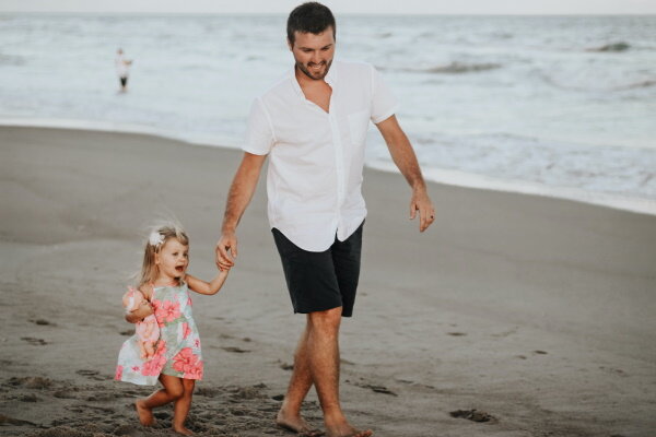 Mann und Kind spazieren am Strand