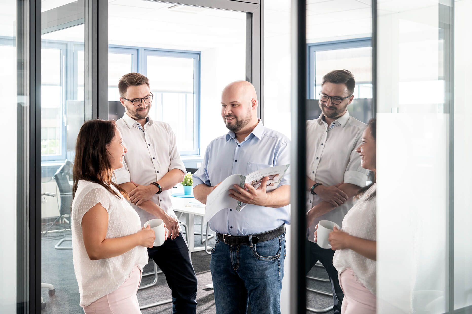 Drei Mitarbeiter besprechen ein Projekt an der Tür zum Besprechungsraum. 